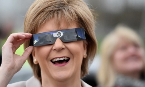 Nicola Sturgeon uses protective glasses to look into the sky at a partial solar eclipse in Glasgow, Scotland. Photograph: Jeff J Mitchell/Getty Images 